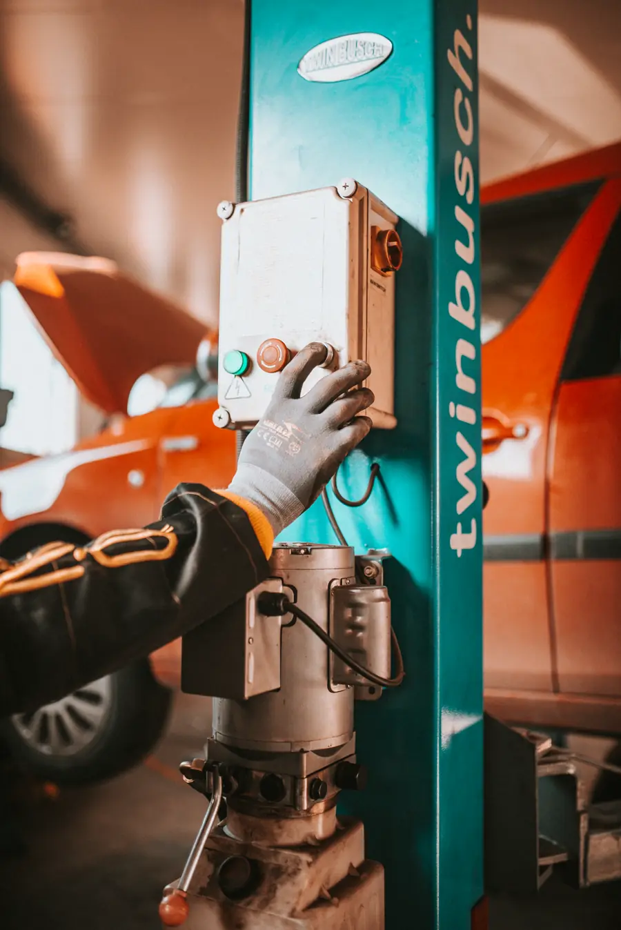 Mâna unui tehnician pe comanda elevatorului auto din atelier